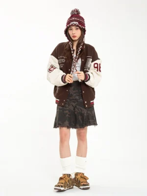 Female model wearing brown camouflage rivet platform skate sneakers with a vintage varsity jacket denim skirt and beanie