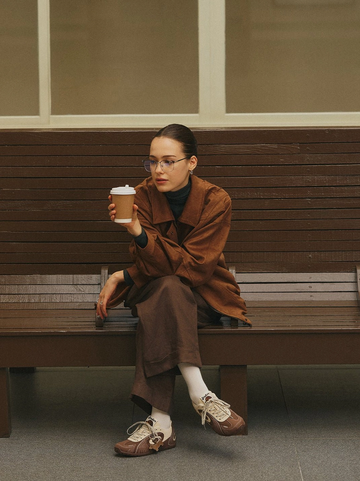 Brown and cream retro trainers worn with a relaxed matching brown outfit during a casual coffee break