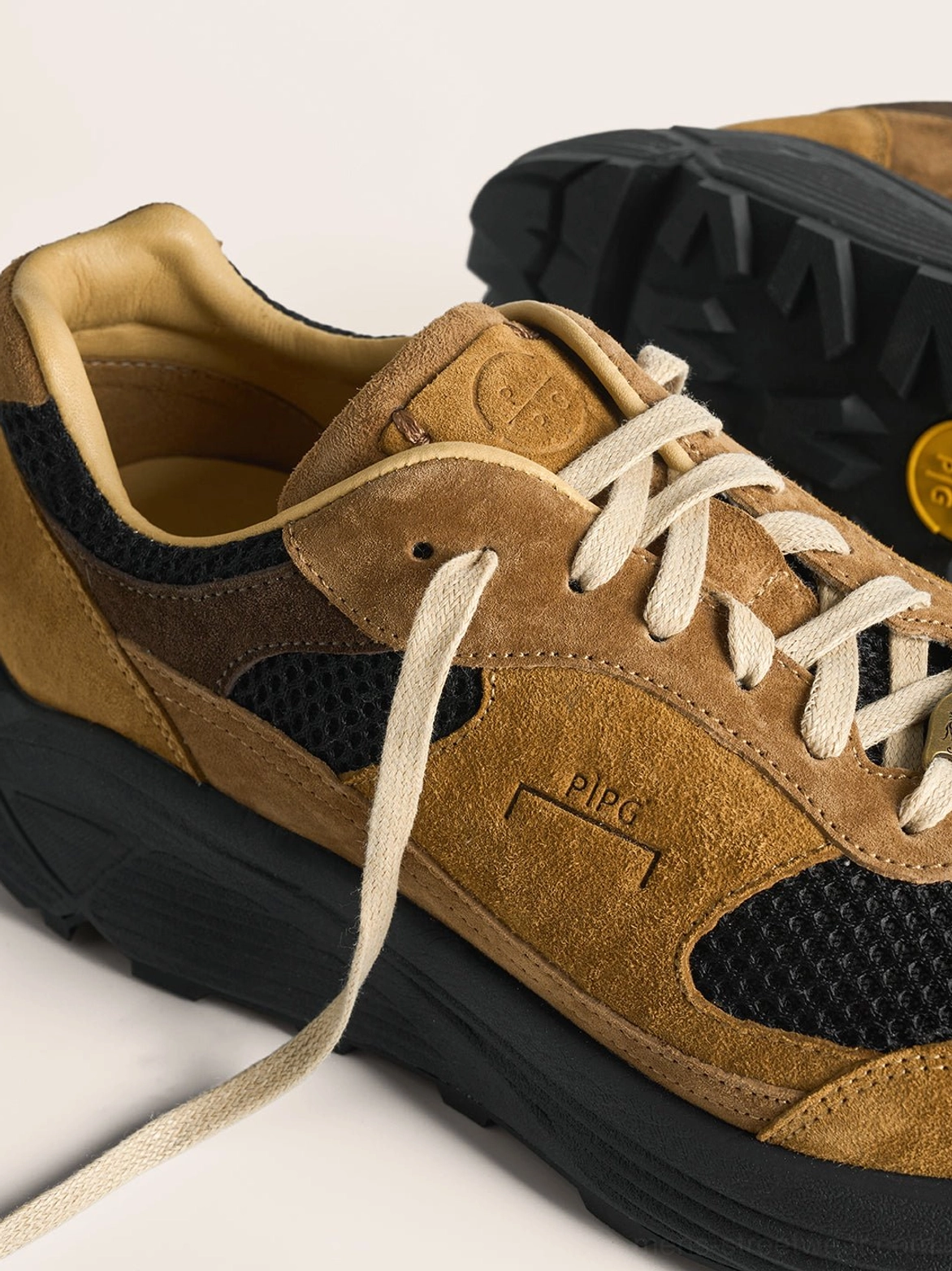 Side view of brown distressed suede trail runner sneaker showing black mesh upper and rugged lugged rubber outsole