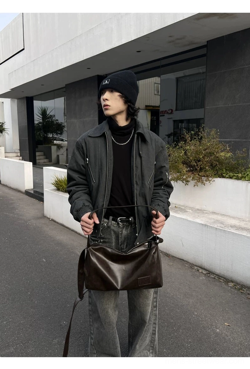 Brown flexible leather-look crossbody shoulder bag shown with a dark jacket and jeans in a modern city street
