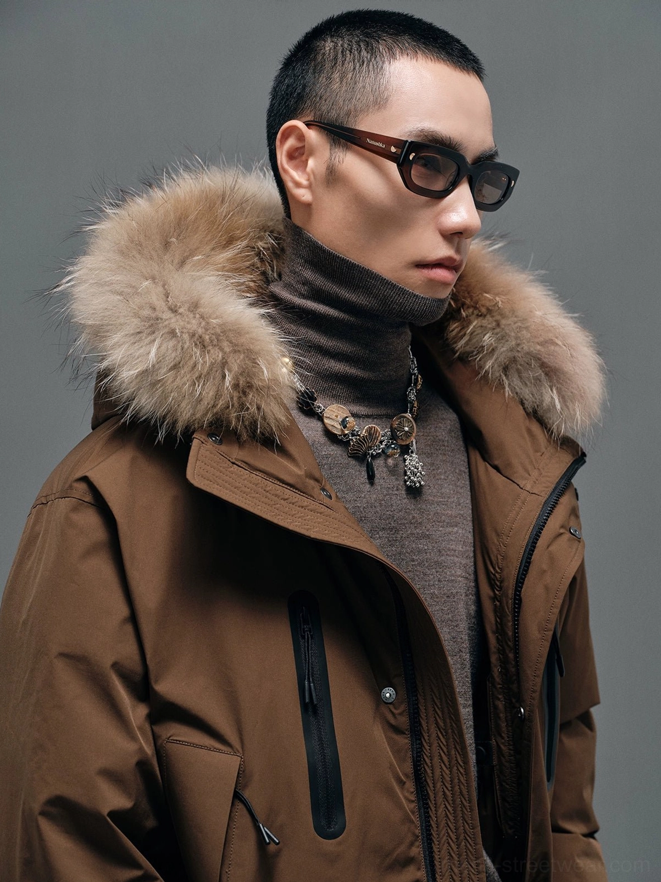 Brown fur-collar hooded down coat close-up showing matte fabric, fluffy collar and contrasting black zipper pocket