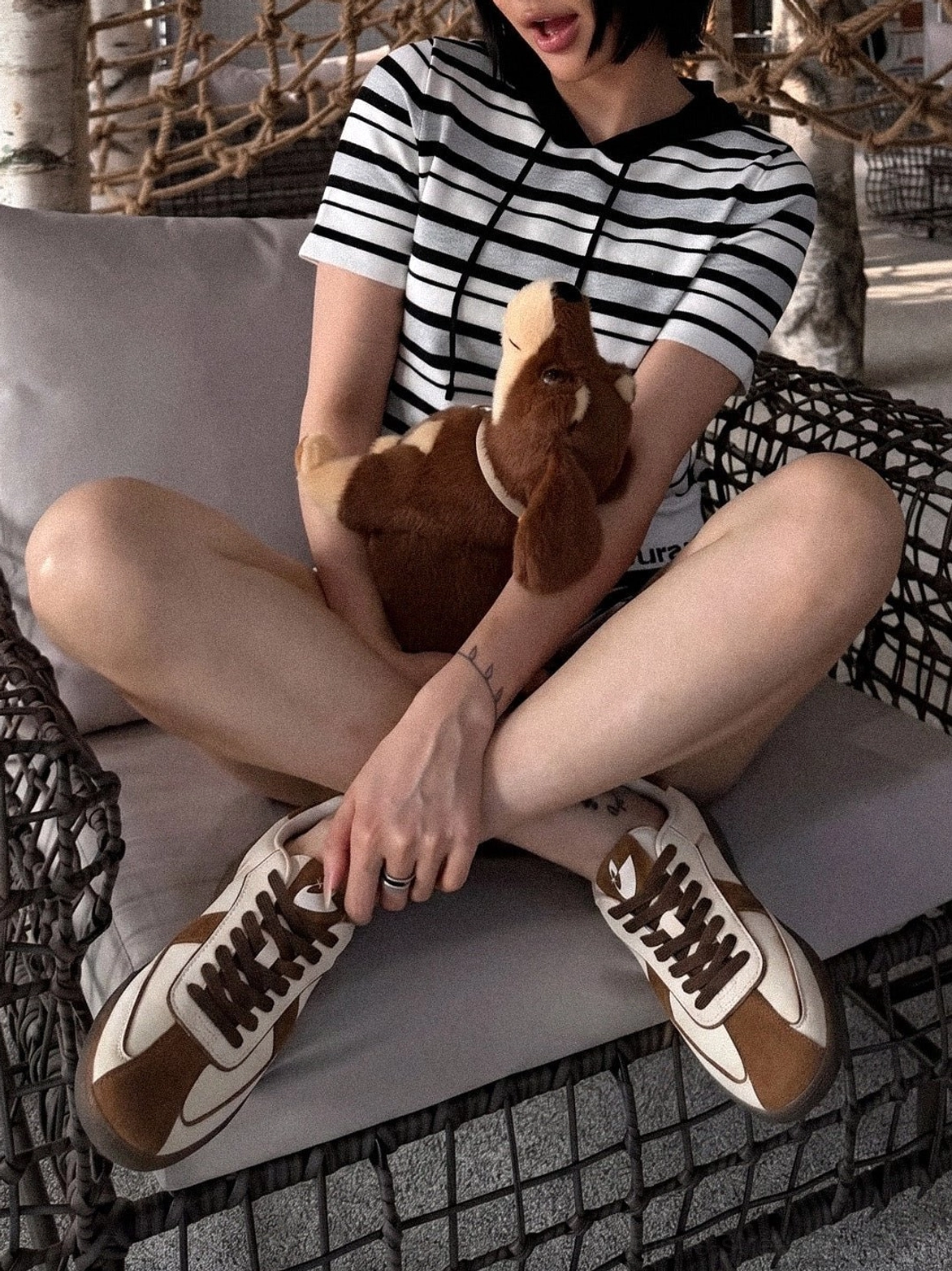 Brown gum sole low profile sneakers worn with a striped top in a relaxed outdoor casual streetwear setting