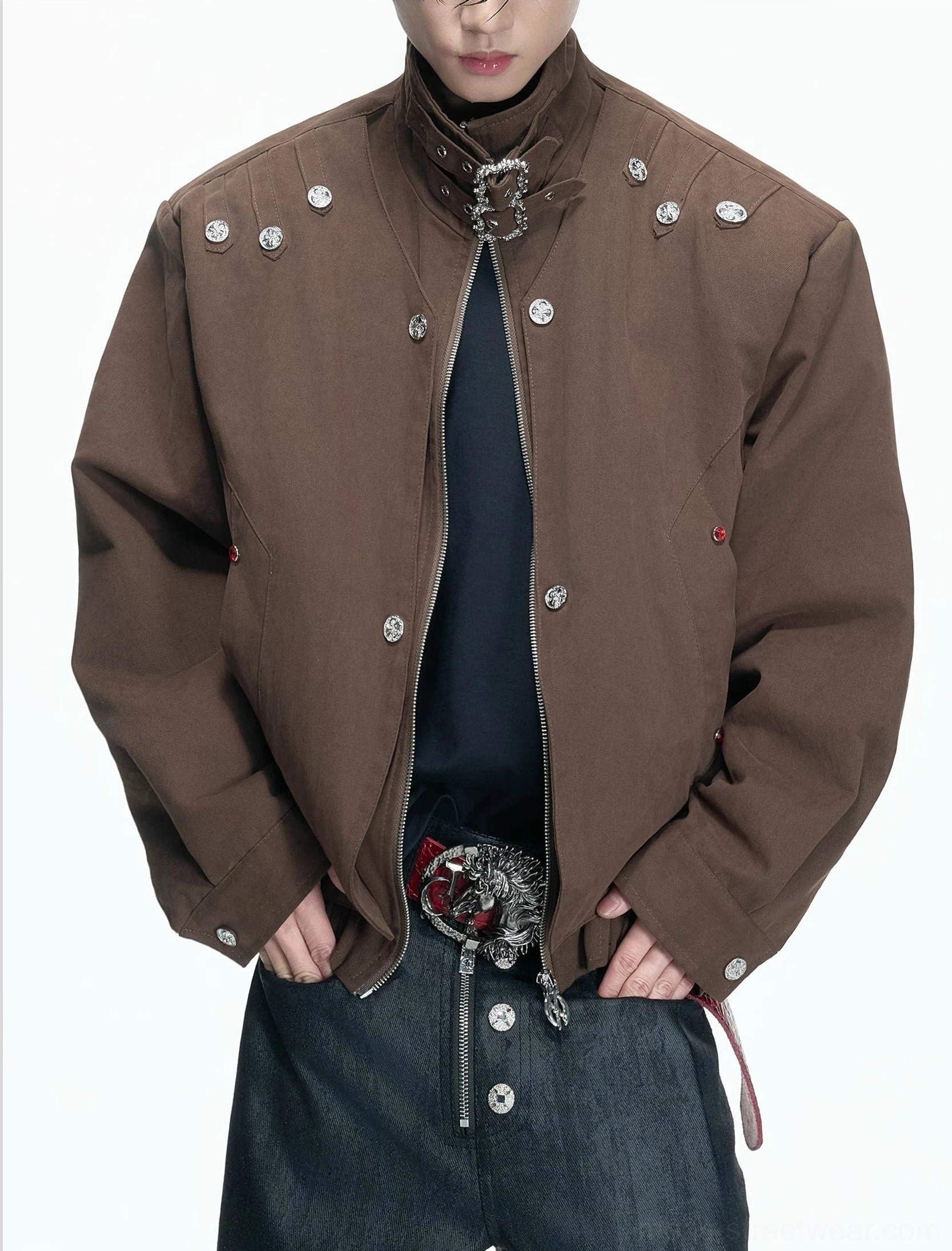 Brown high neck hardware canvas jacket worn by male model with silver buckle collar, metal rivets, and cropped streetwear fit