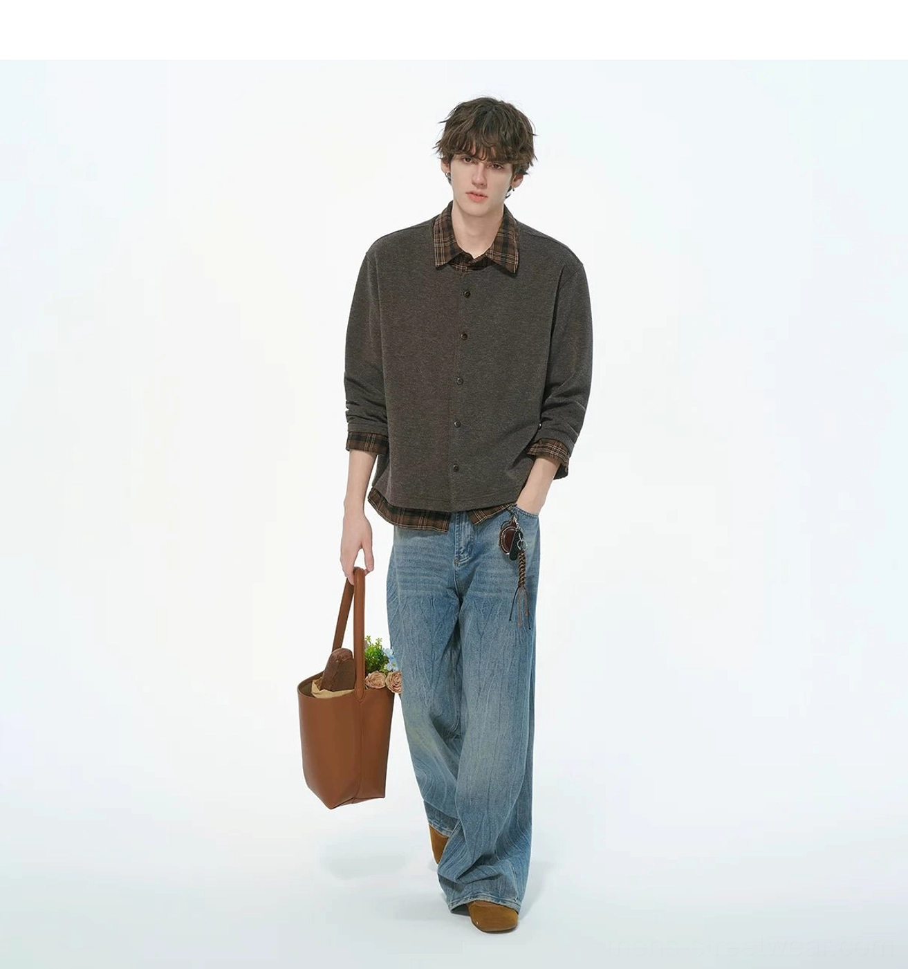 Male model walking in a heather brown plaid collar knit shirt jacket with blue wide-leg jeans and a tote bag