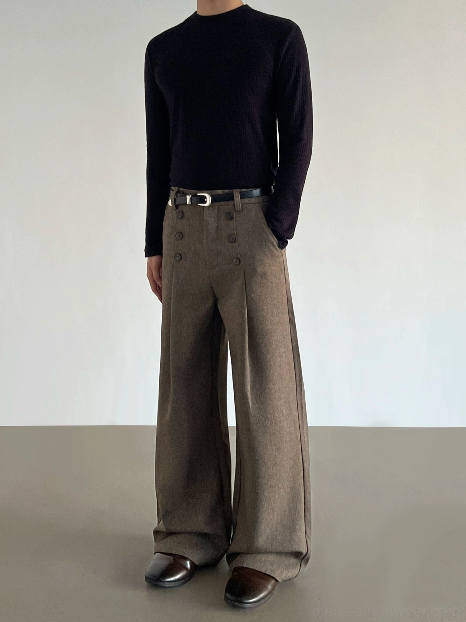 Side-front view of brown pleated wide-leg trousers with twin decorative waist buttons, relaxed tailoring, and modern Seoul streetwear styling