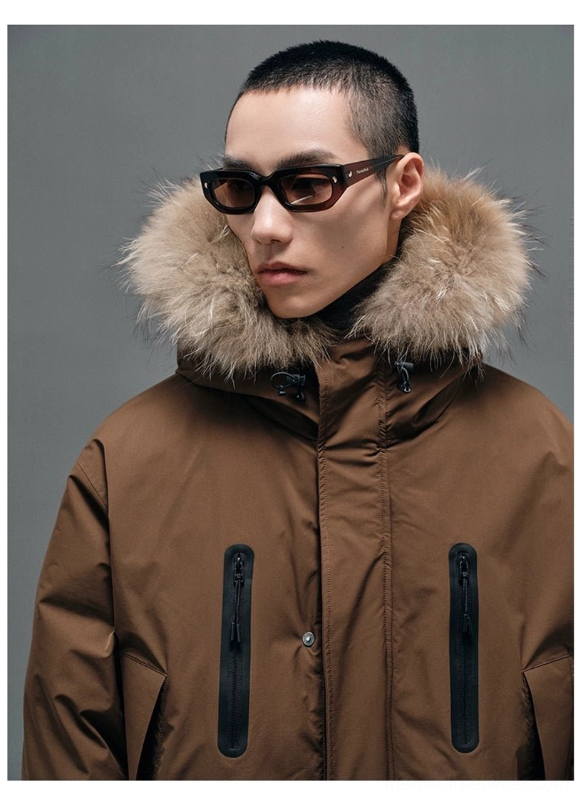 Close-up portrait view of brown hooded down coat with thick raccoon fur collar, black vertical zipper pockets and button placket