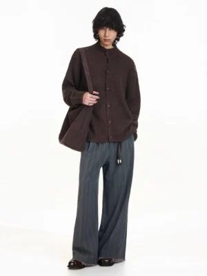 Brown relaxed fit stand collar knit cardigan with contrasting red buttons and brown tote bag three-quarter view