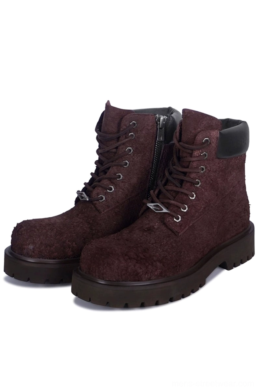 Dark brown suede combat boots with chunky black lug soles and side zipper, shown in a front three-quarter studio view