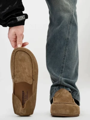 Brown suede driving loafers showing the rear profile, moc toe stitching, cushioned insole, and slip on design