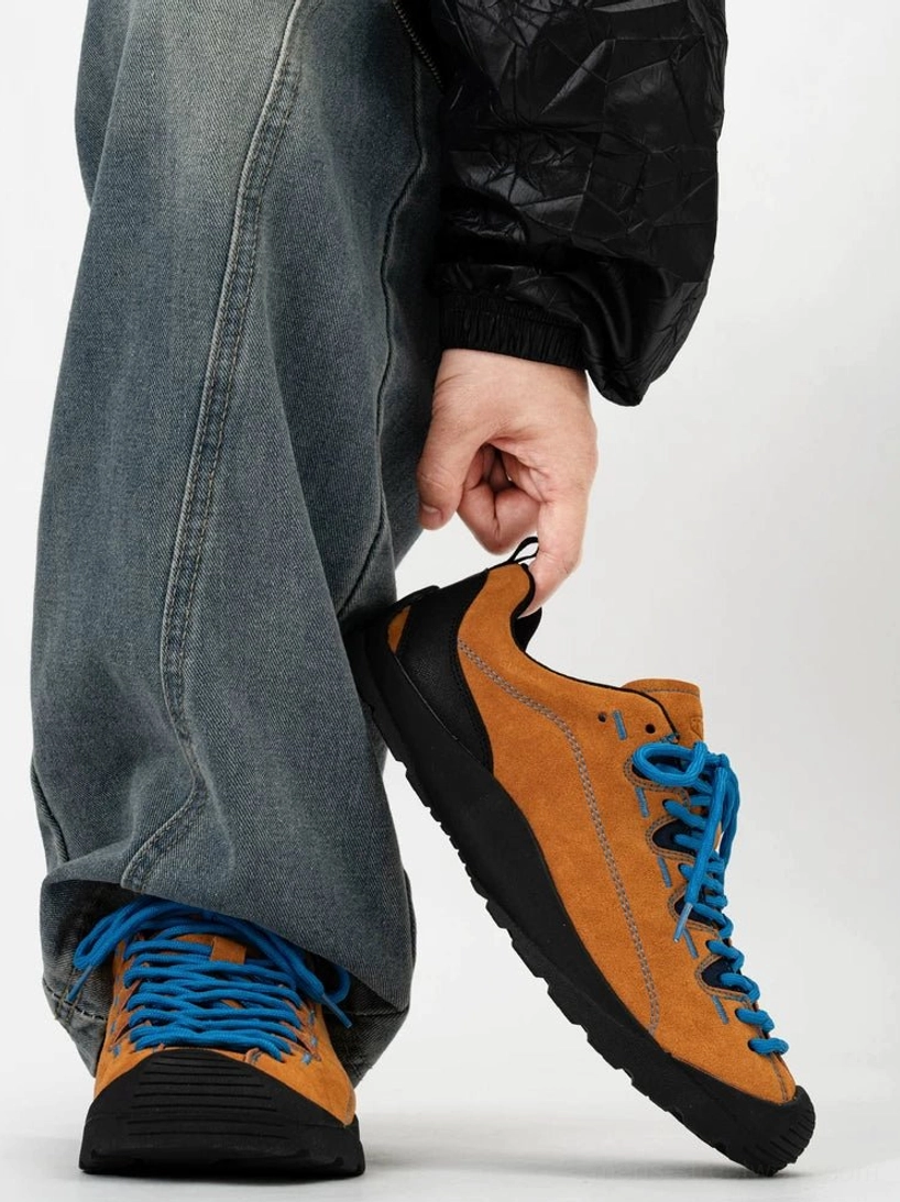 Brown suede gorpcore trail sneakers with contrast blue laces and black rubber sole shown from side and rear on foot