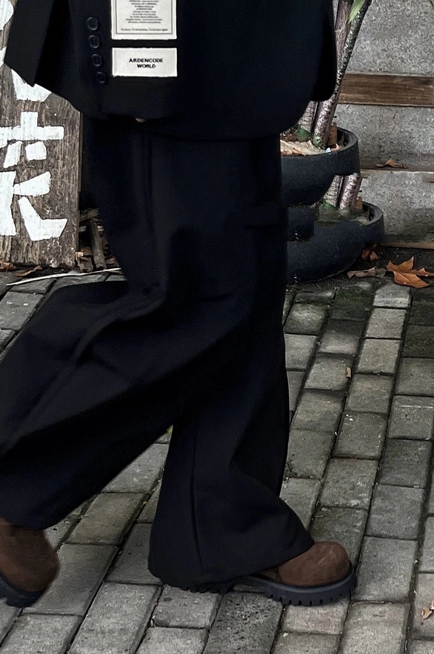 Brown suede lug-sole derby shoes styled with an all-black tailored outfit and wide-leg trousers