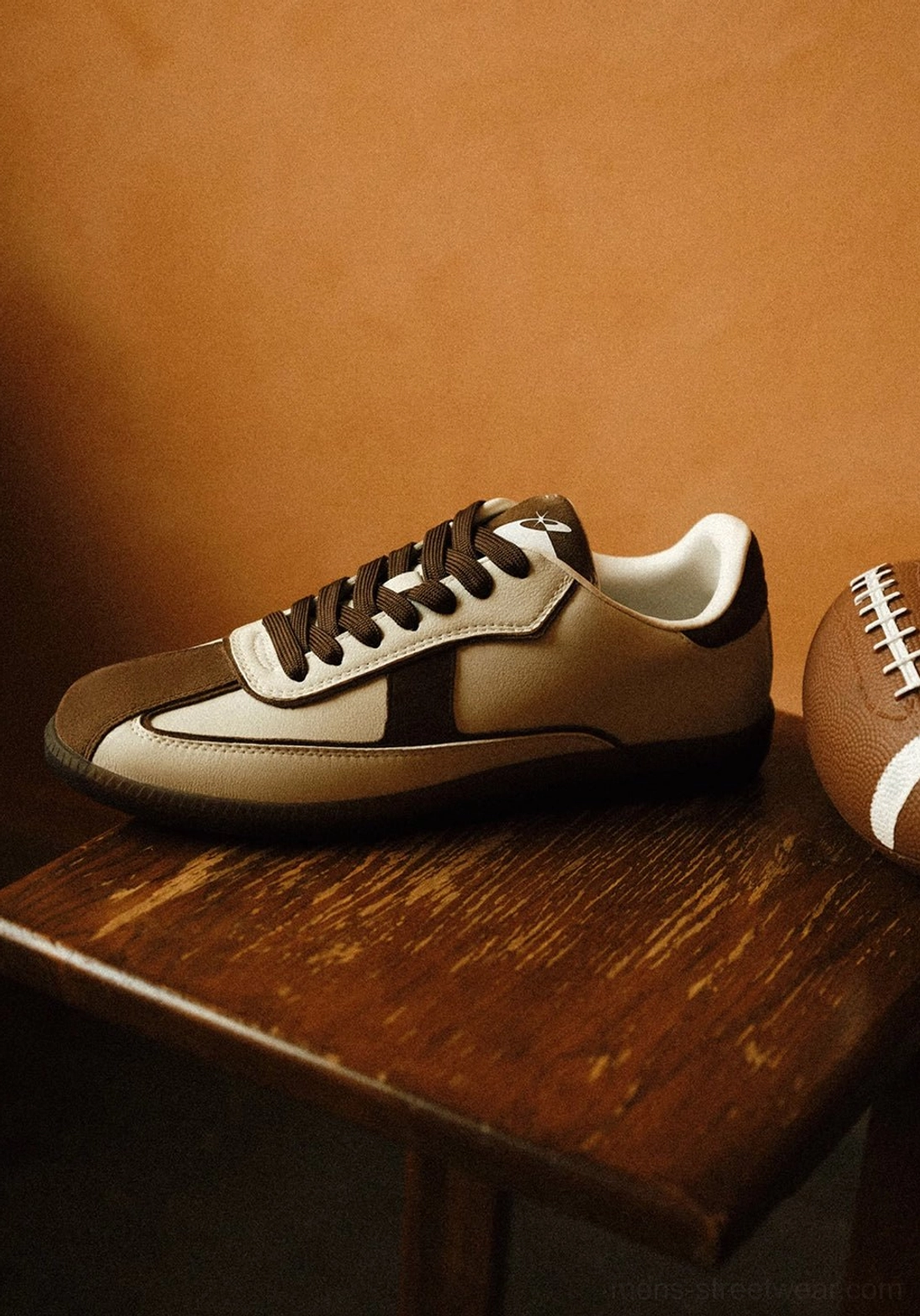 Brown suede panel trainers displayed beside a rugby ball showing tonal overlays brown laces and gum rubber outsole