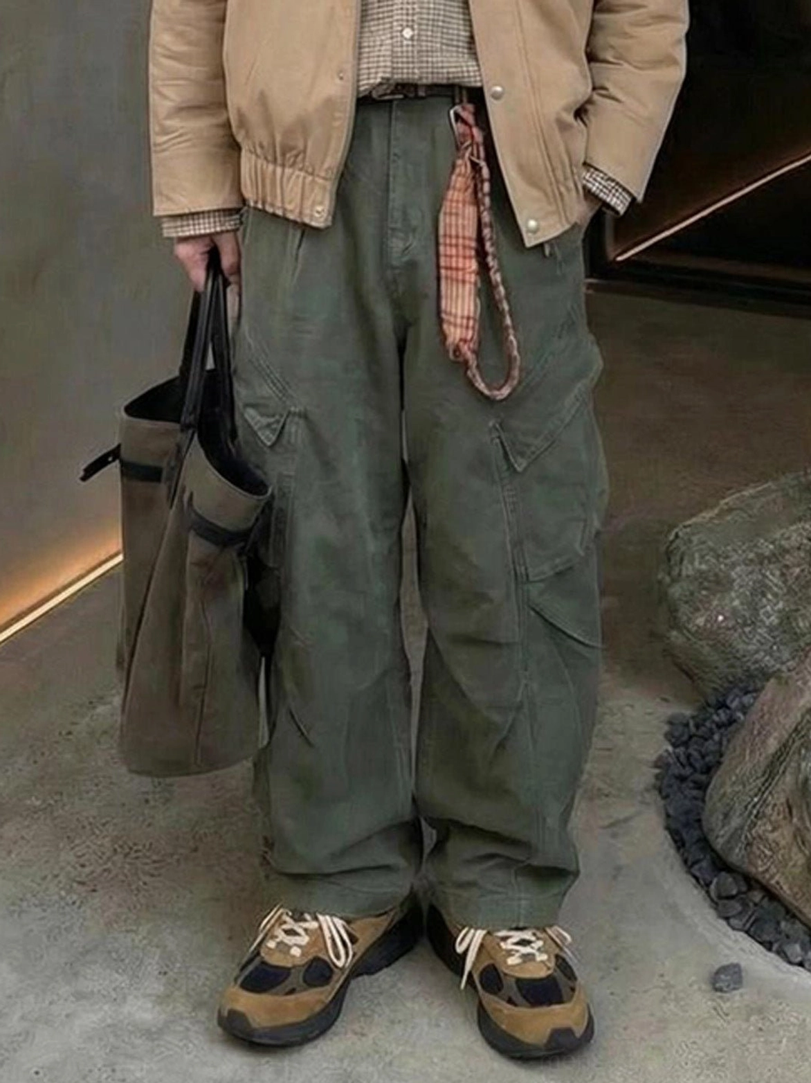 Brown suede trail runner sneakers worn with khaki jacket green cargo pants and industrial streetwear styling