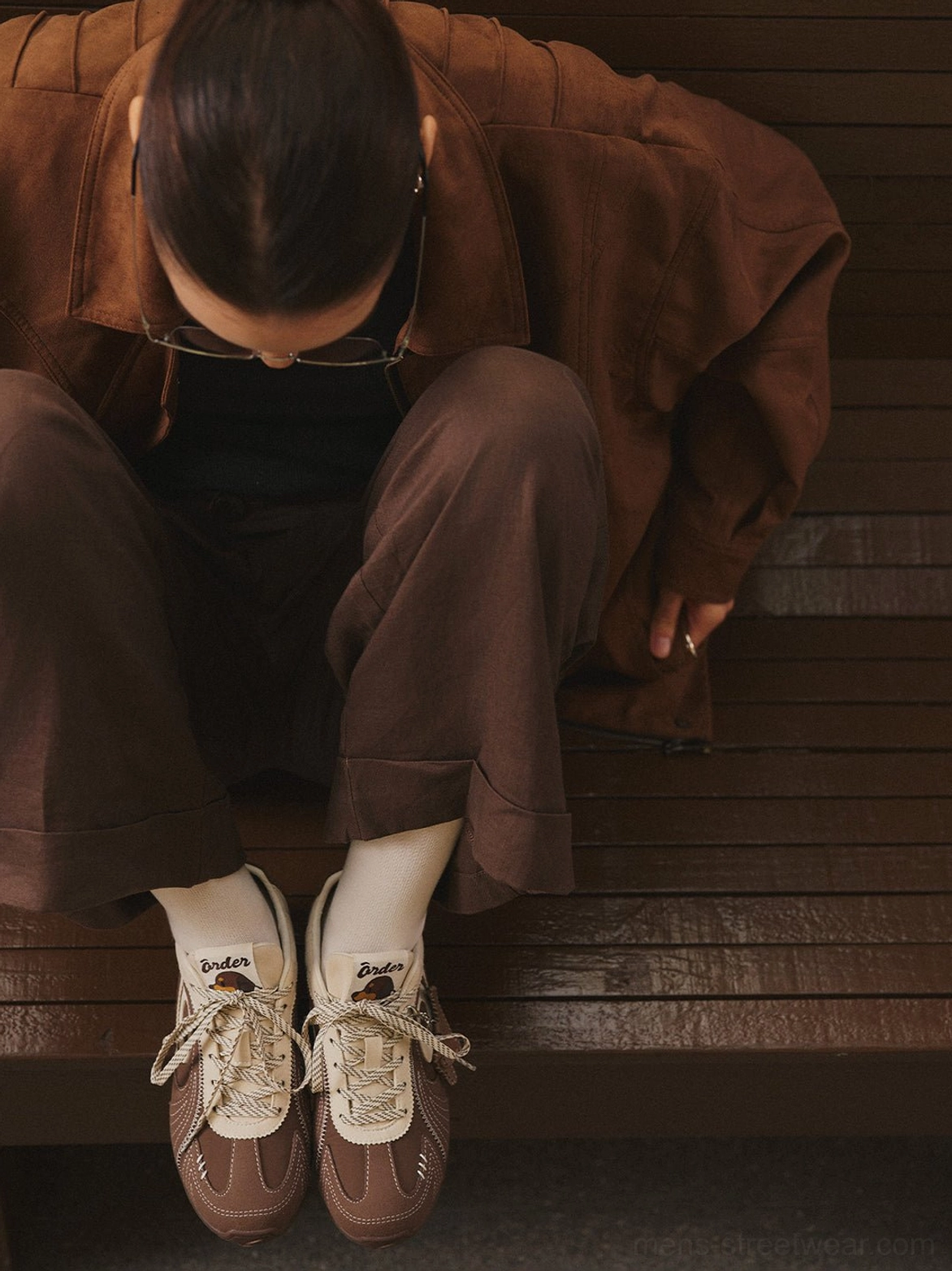 Front low-angle view of brown swirl panel retro trainers worn with a coordinated casual brown outfit