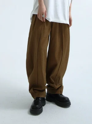 Brown textured wide-leg streetwear trousers front view showing relaxed drape vertical seam details and pleated waist