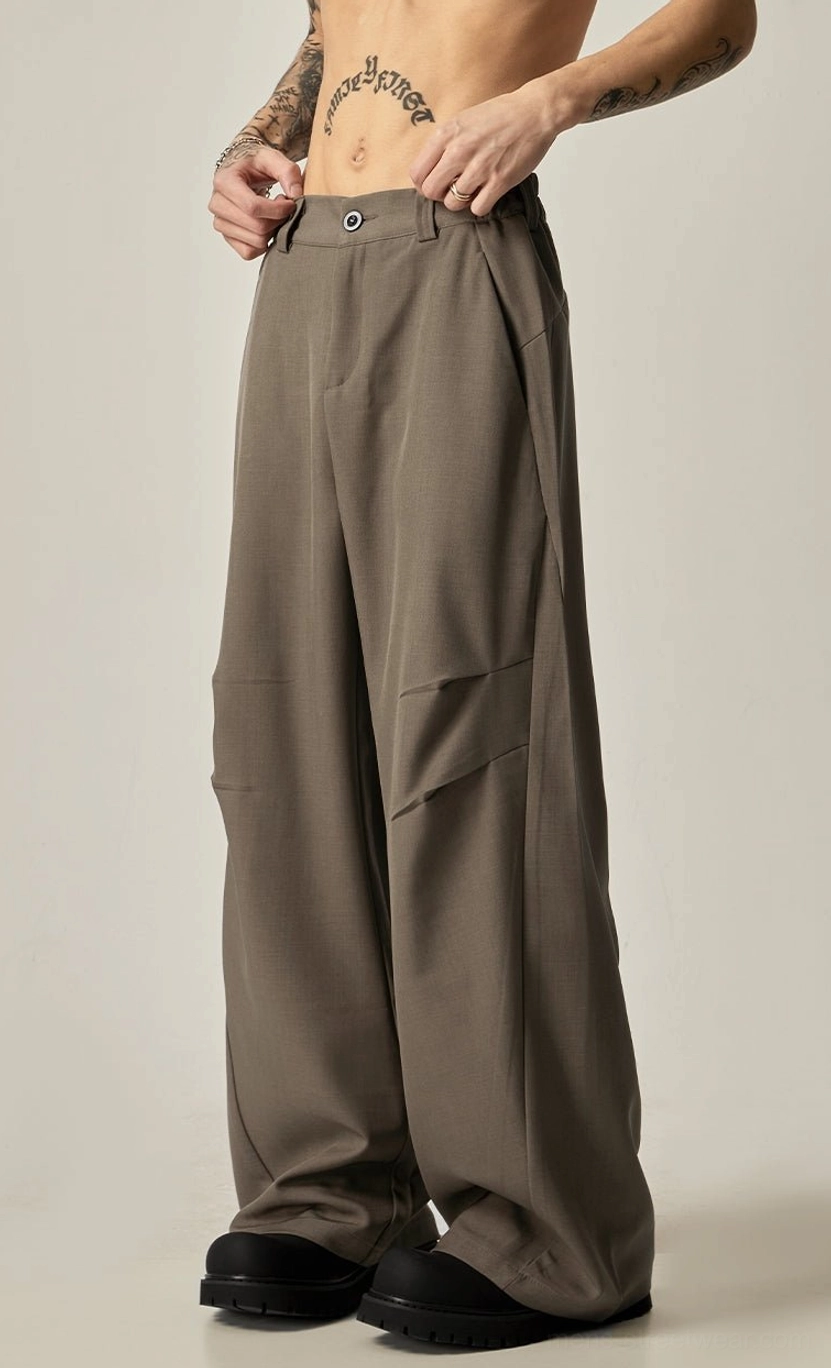 Brown ultra-wide leg tailored trousers three-quarter front view showing structured front seam details and wide flowing hem