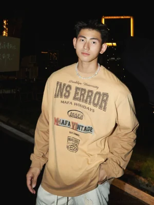 Brown vintage university graphic sweatshirt with retro collegiate chest print styled for Korean streetwear at an outdoor night venue