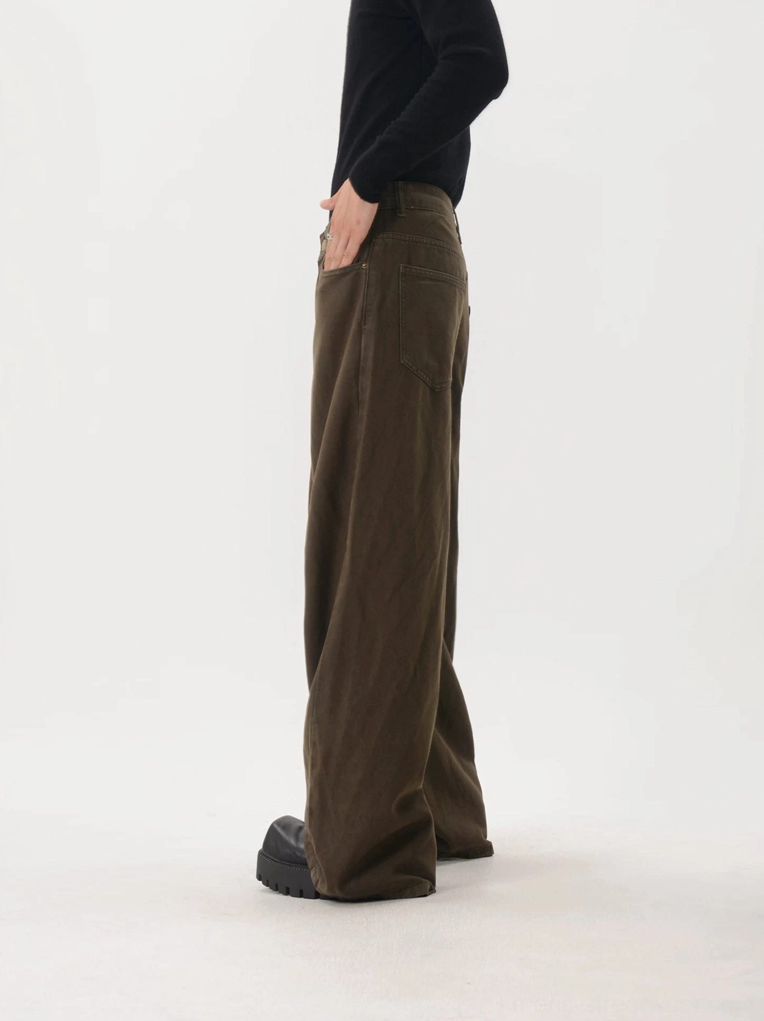 Side view of dark brown washed wide-leg pants featuring loose draped legs, visible side seams, back pocket construction, and relaxed Japanese-inspired streetwear proportions