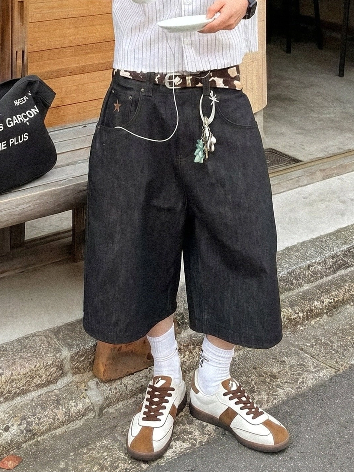 Brown and white suede retro sneakers paired with black wide denim shorts for a relaxed vintage streetwear outfit