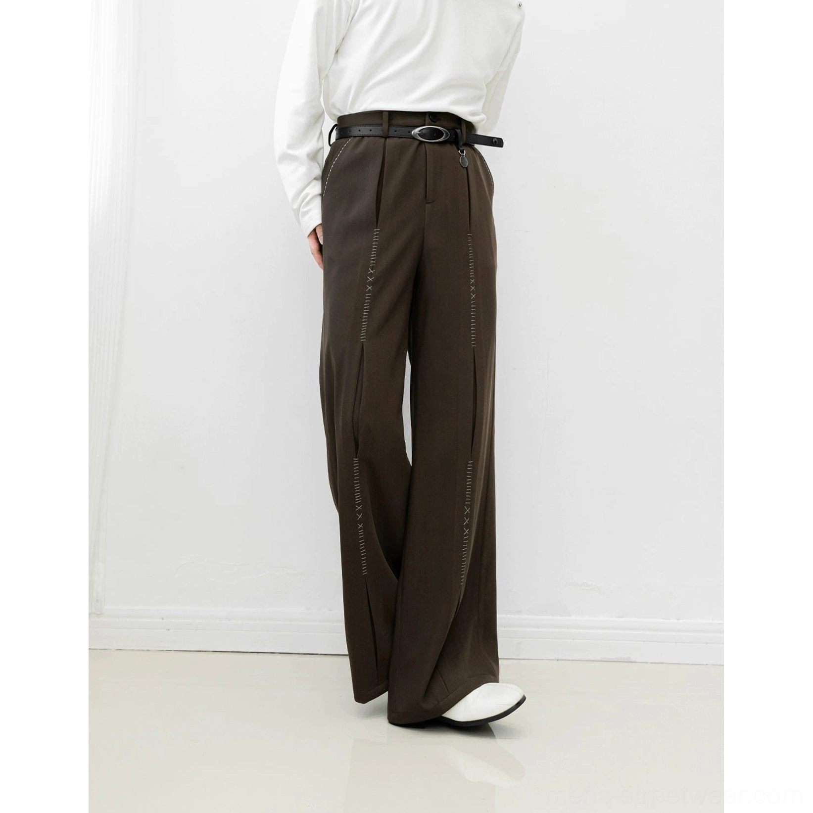 Brown wide-leg streetwear trousers shown from the side rear angle with flowing fabric, high waist, black belt, and stitched leg detailing