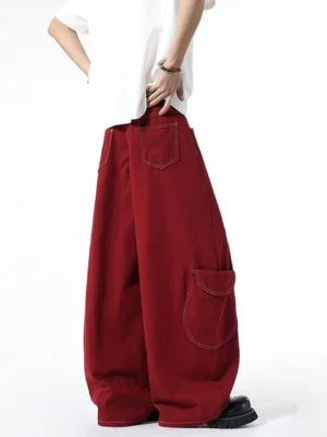 Back view of oversized burgundy cargo denim pants showing relaxed baggy wide-leg fit, rear patch pocket, contrast stitching, and deep red cotton denim