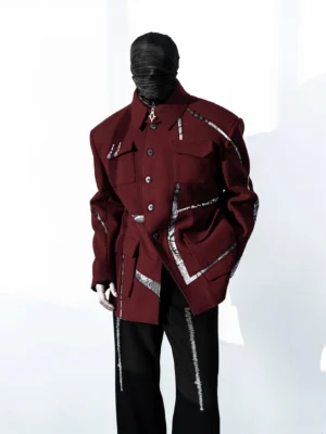 Three-quarter front view of burgundy industrial streetwear field jacket with button front, utility pockets, and irregular silver trim details