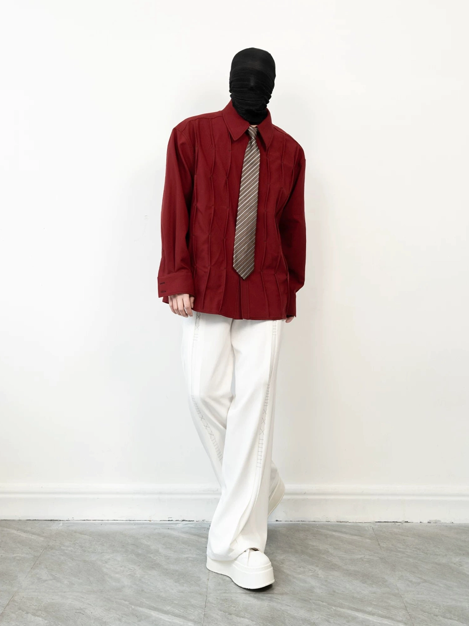 Burgundy Korean streetwear shirt with geometric pleated texture and striped tie worn with white trousers and sneakers