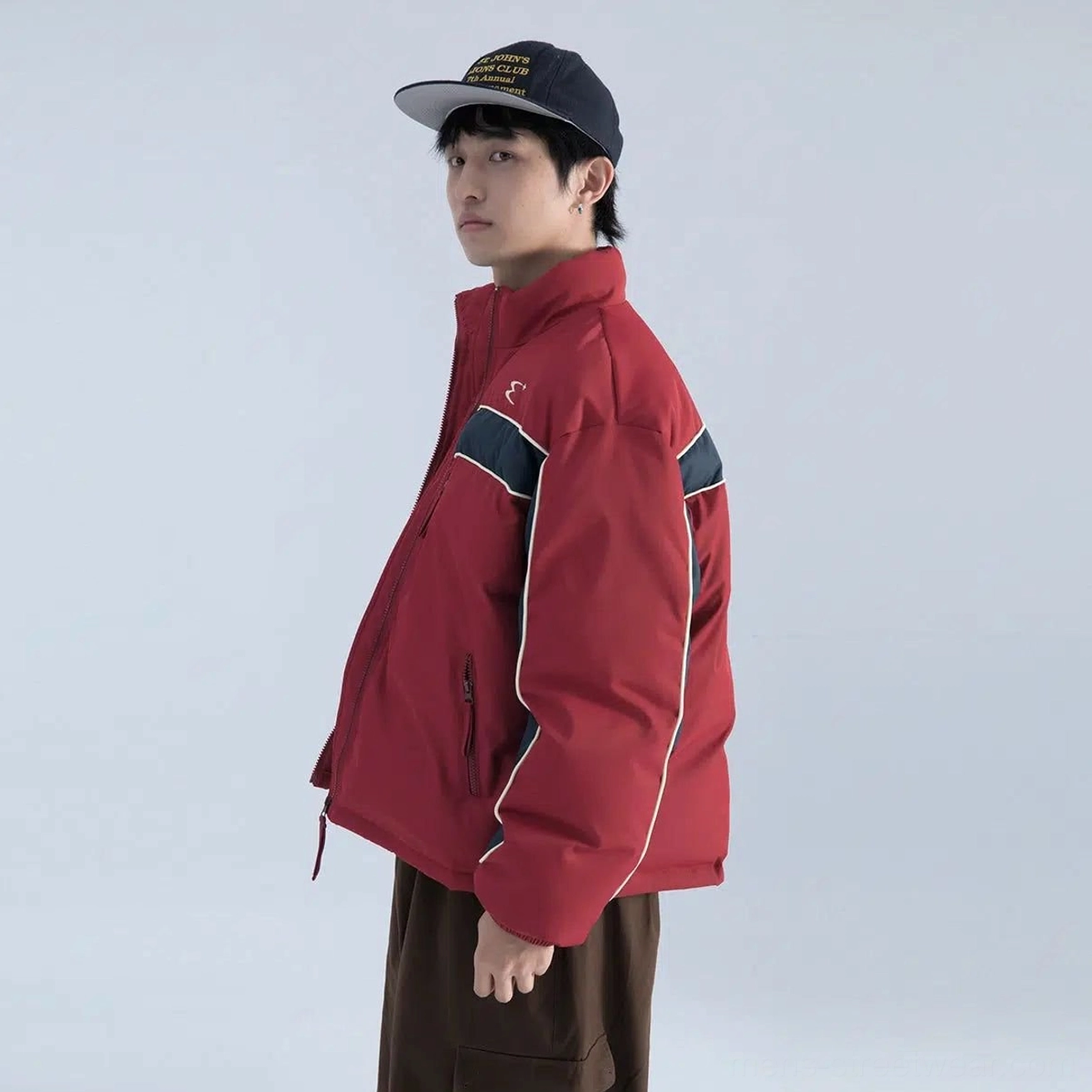 Side view of burgundy red and navy color block boxy puffer jacket showing relaxed fit stand collar and zip pocket