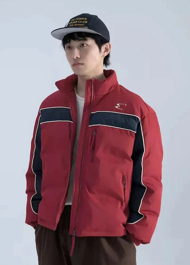 Burgundy red and navy color block boxy puffer jacket worn by male model with stand collar contrast piping and zipper pockets
