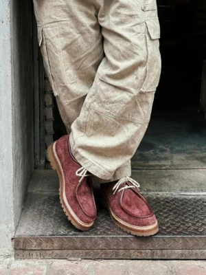 Burgundy suede work loafers styled with beige cargo pants on a metal step in casual streetwear outfit