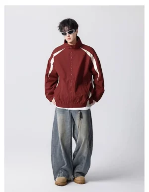 Front view of a burgundy streetwear track windbreaker styled with wide-leg jeans and tan boots