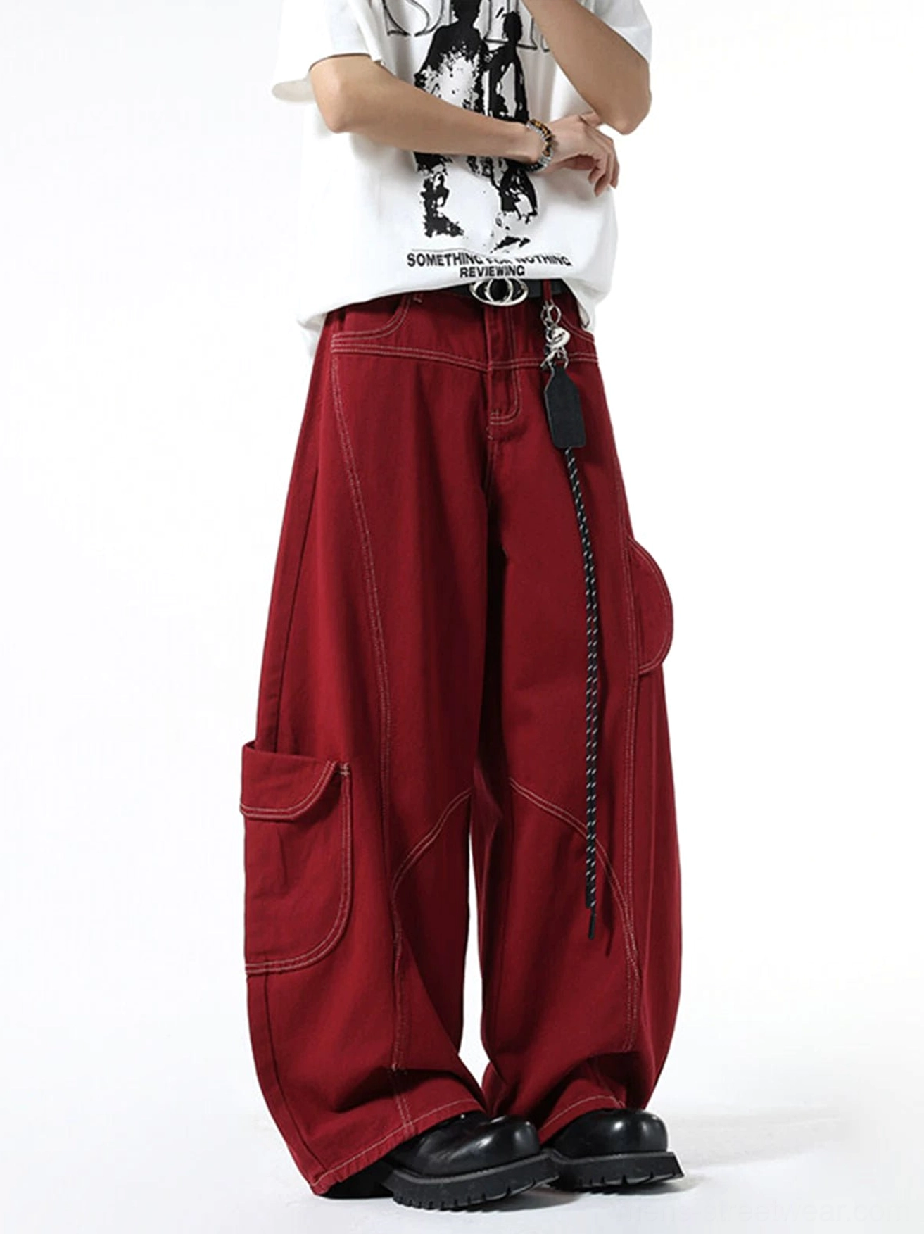 Side view of burgundy wide-leg streetwear cargo pants highlighting curved topstitching, side cargo pocket, oversized silhouette, and relaxed denim drape