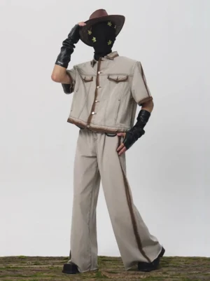Full body view of a faded oat cropped denim jacket styled in a Western Korean streetwear outfit with burnished brown trim and wide leg denim pants