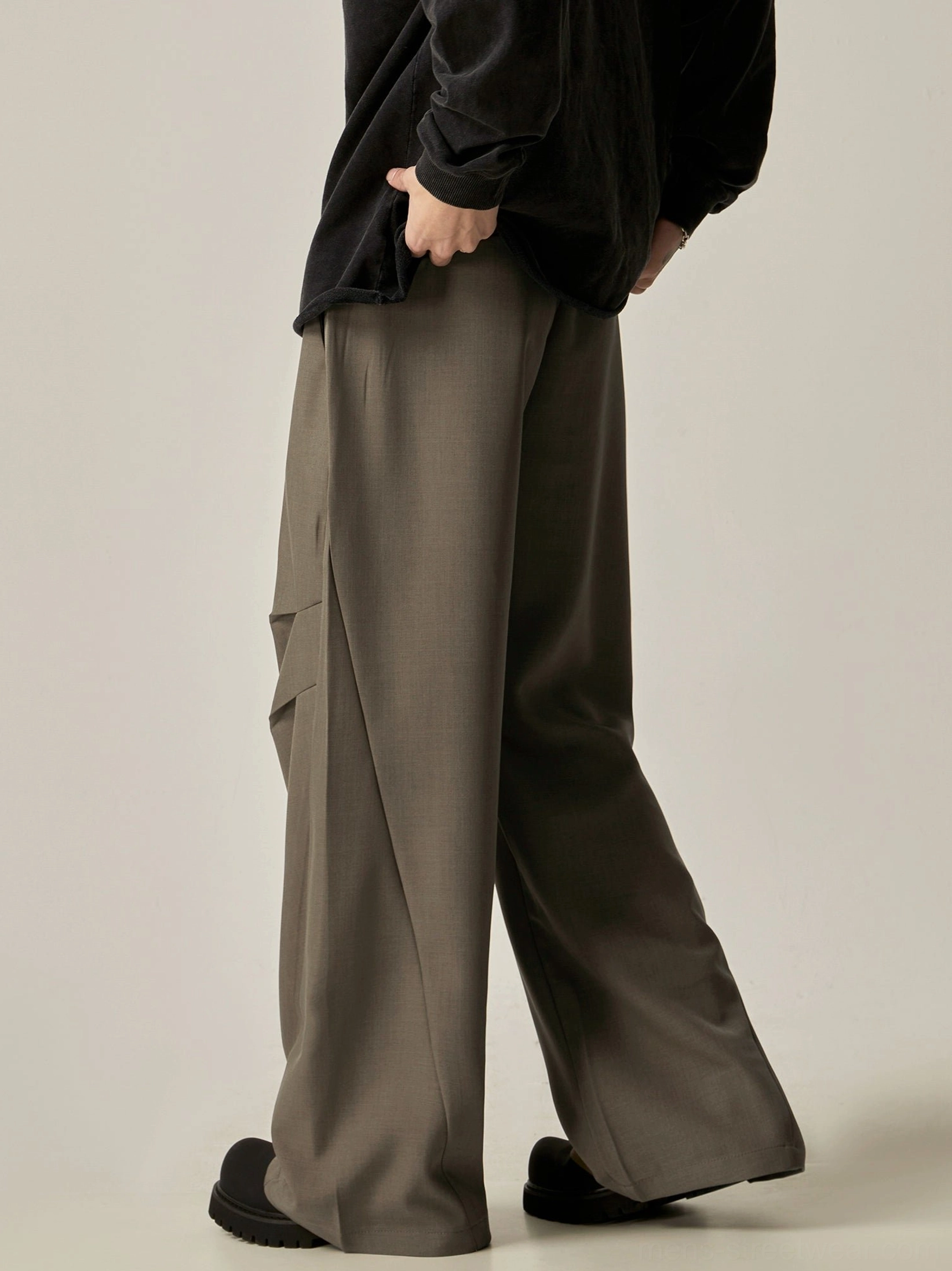 Camel taupe wide-leg trousers shown from the rear side with flowy legs, structured pleated cargo pockets, and muted neutral color
