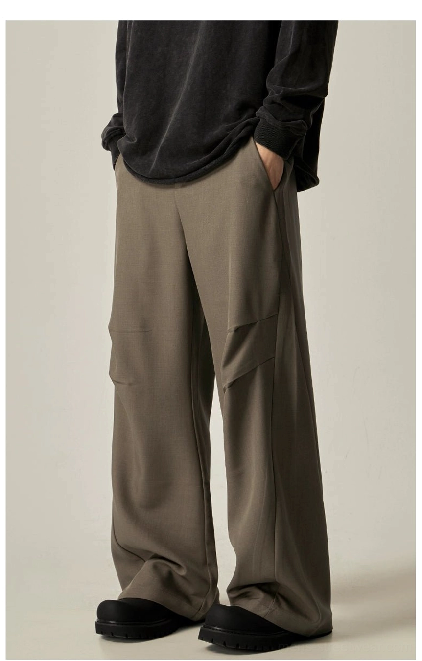 Camel wide-leg utility trousers with relaxed drape, neutral taupe color, pleated side pockets, and black loafer styling
