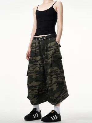 Front view of women wearing tiger stripe camouflage cargo capri culottes with a relaxed wide leg cropped silhouette, black camisole, leather belt, white socks and sneakers