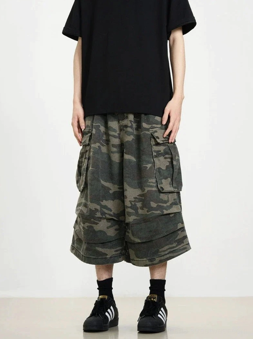 Front view of dark camouflage cargo wide-leg cropped shorts with oversized side pockets and layered hem styled with a black streetwear tee
