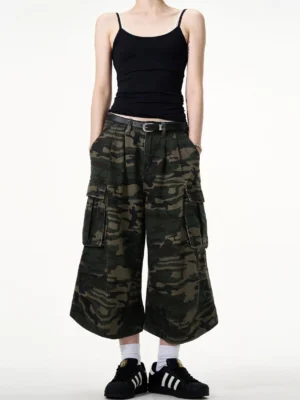 Front streetwear outfit featuring camouflage cargo culottes with pleated waist, oversized utility pockets, black top, belt and casual sneakers