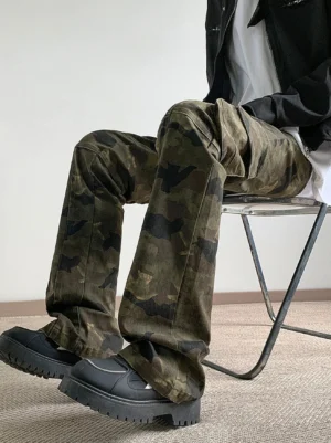 Seated side view showing the relaxed fit fabric texture and large flap cargo pockets of dark green camouflage streetwear pants with black work boots