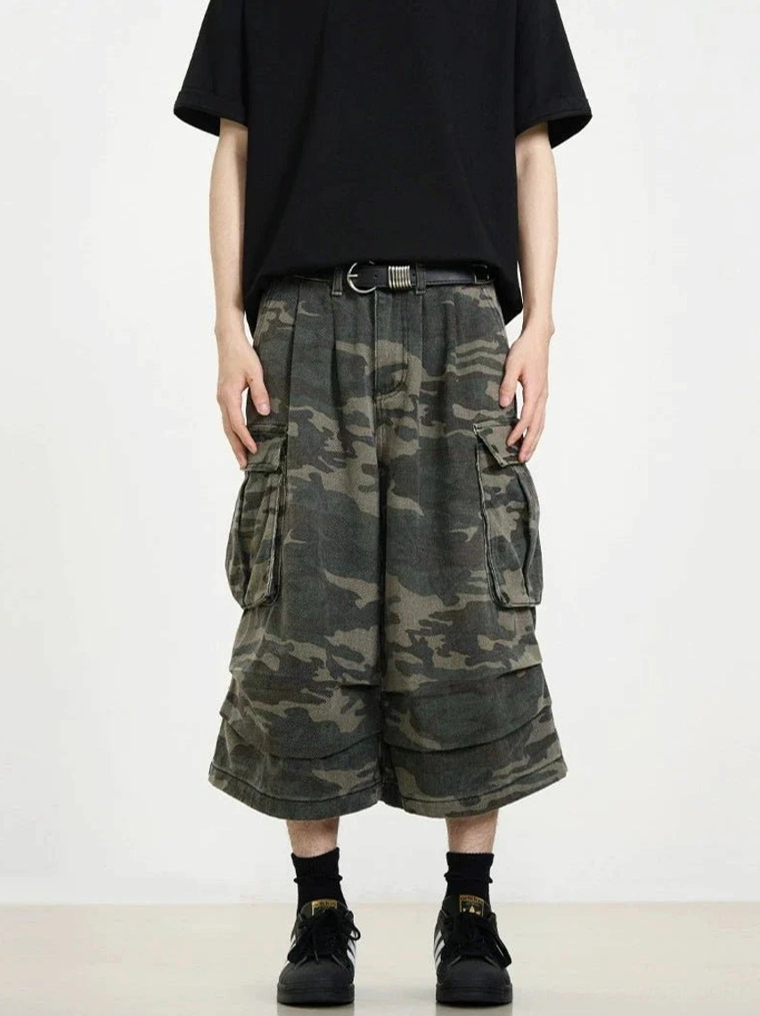 Camouflage wide-leg cargo shorts styled with a leather belt, black tee, and casual footwear for an urban utility outfit