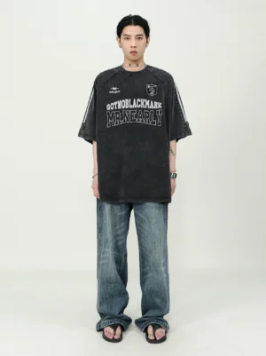 Full-body styling of a carbon black oversized varsity jersey T-shirt with washed wide-leg jeans and casual sandals
