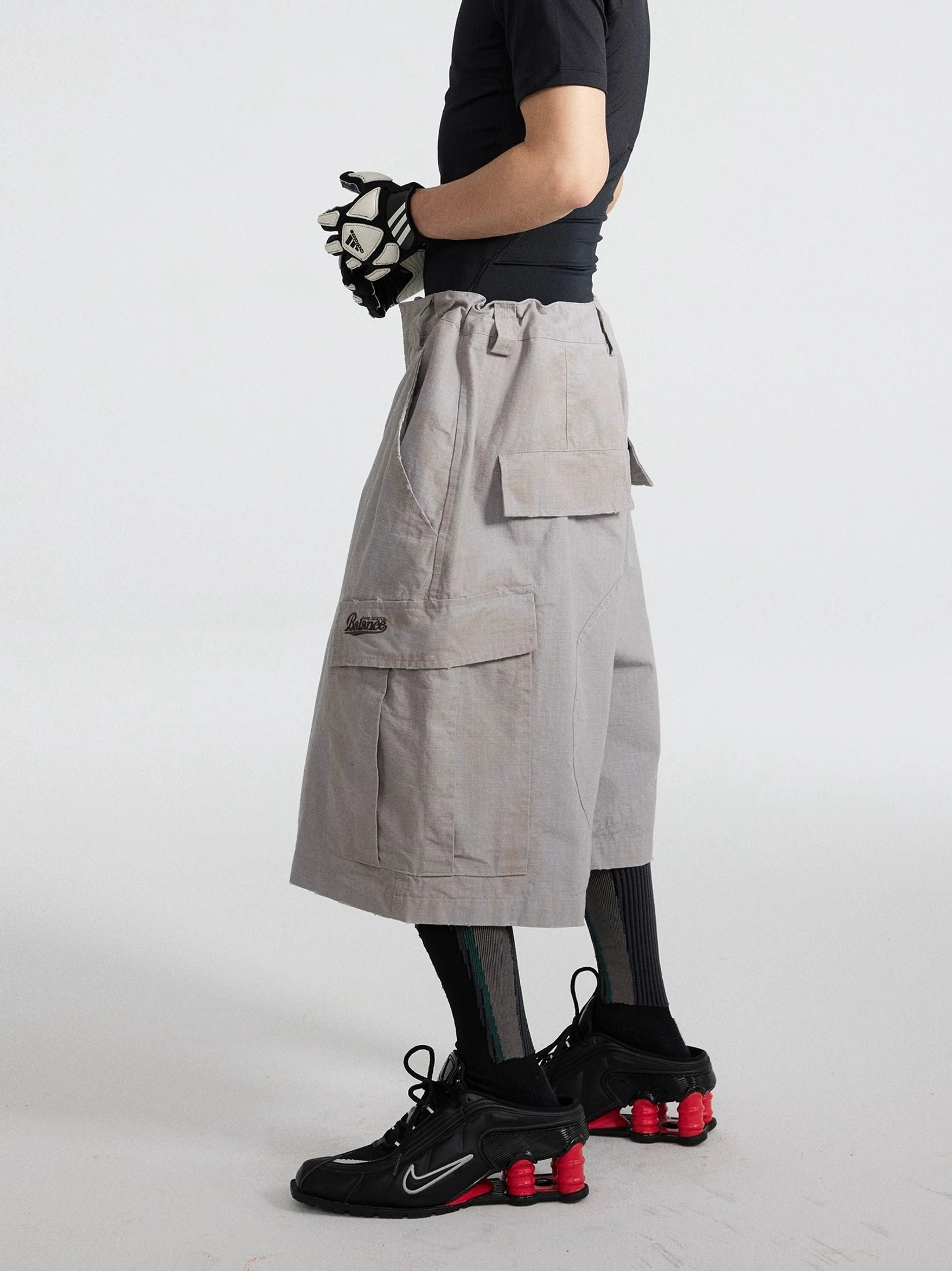 Side view of cement ash utility cargo culottes showing drawstring waist detail, embroidered side pocket, and loose silhouette