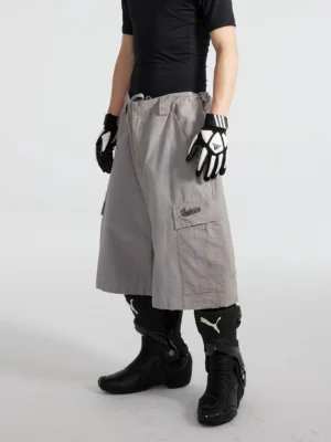 Front full-body view of cement ash wide-leg cargo culottes styled with a fitted black t-shirt, gloves, and black moto boots