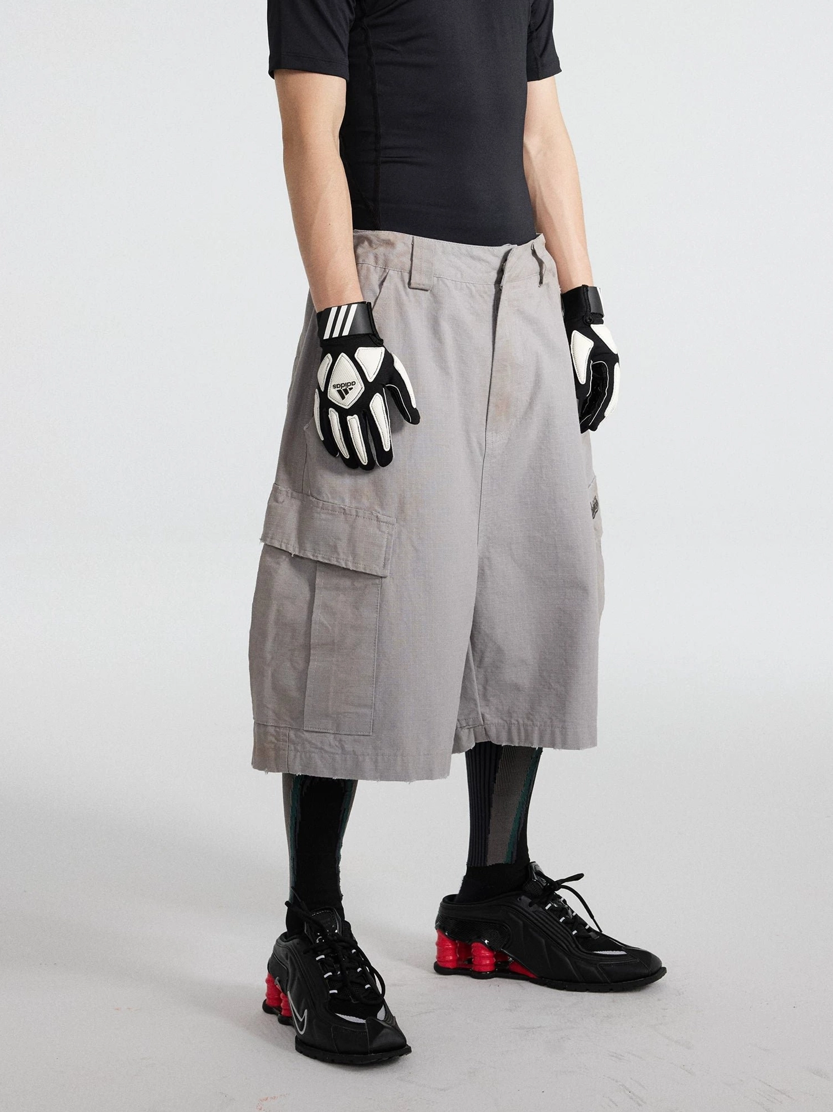 Three-quarter front view of light grey wide-leg cargo culottes with button zip closure and oversized side flap pockets