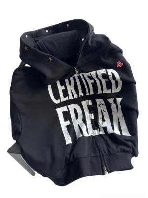 Angled top view of black Certified Freak cropped zip streetwear hoodie showing tall hood metal snaps gold star rivets and ribbed trims