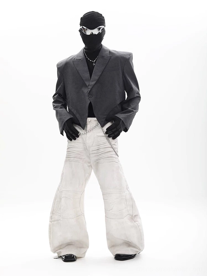 Charcoal gray asymmetric cropped blazer with padded shoulders and pointed front hem styled with white wide leg pants