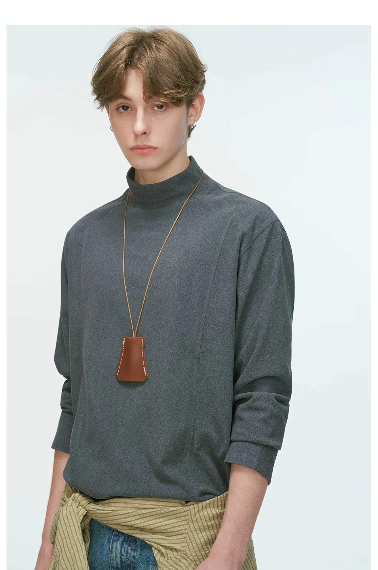 Close-up front view of a charcoal gray men's mock neck long sleeve top styled with a striped shirt tied around the waist