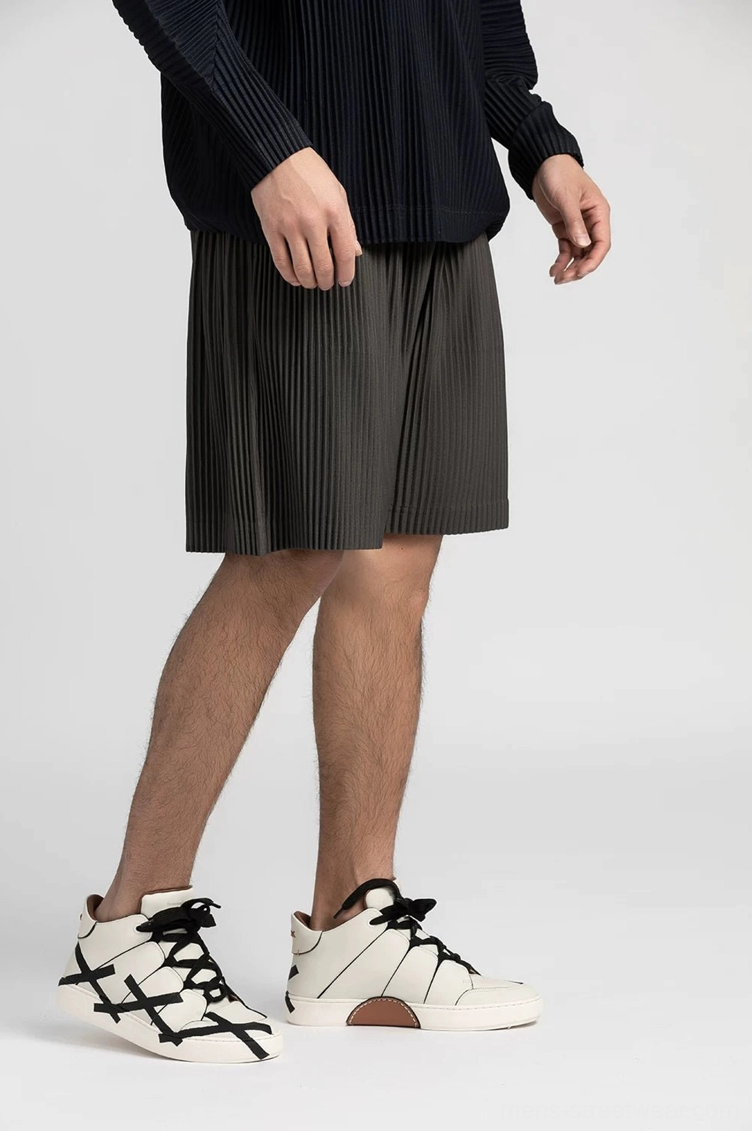 Charcoal gray pleated casual shorts with elastic waistband and relaxed straight legs styled with sneakers