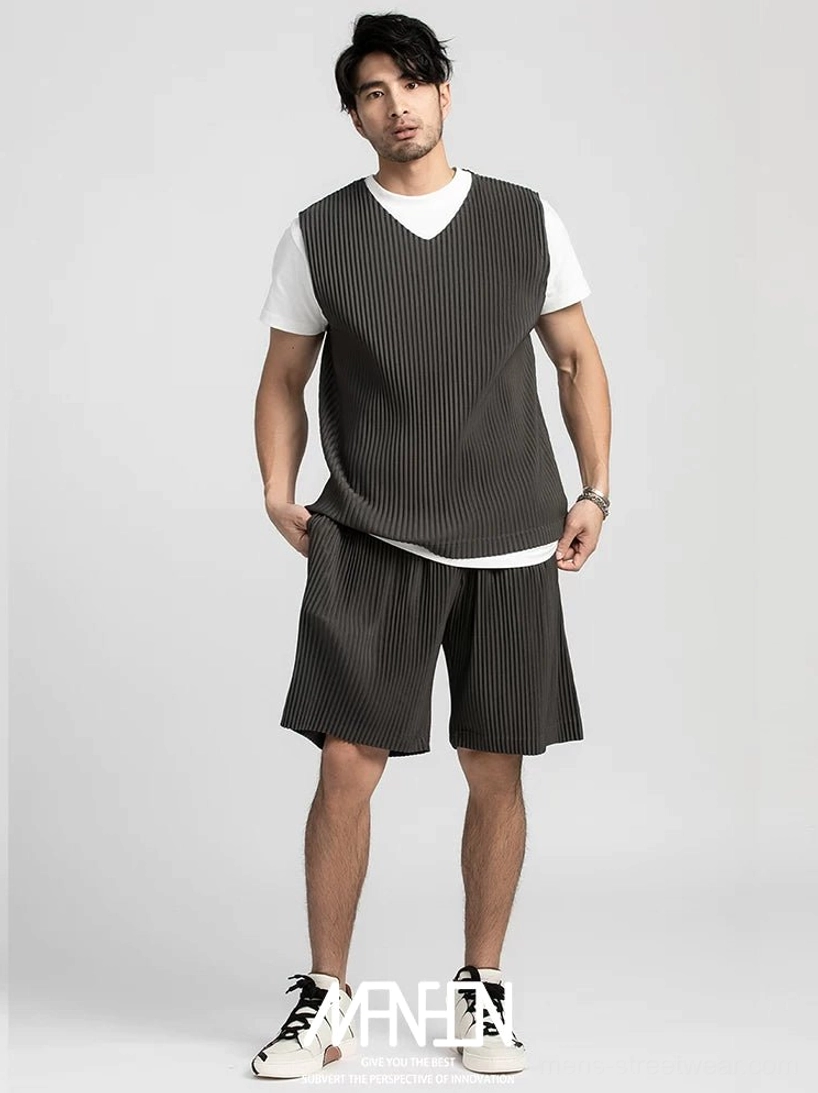 Charcoal gray pleated shorts styled with a matching relaxed vest and layered white tee