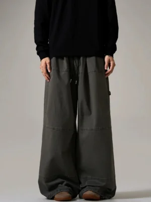 Dark charcoal gray wide-leg cargo skater pants with drawstring waist, contrast panel stitching, side utility loop, and relaxed Seoul streetwear silhouette